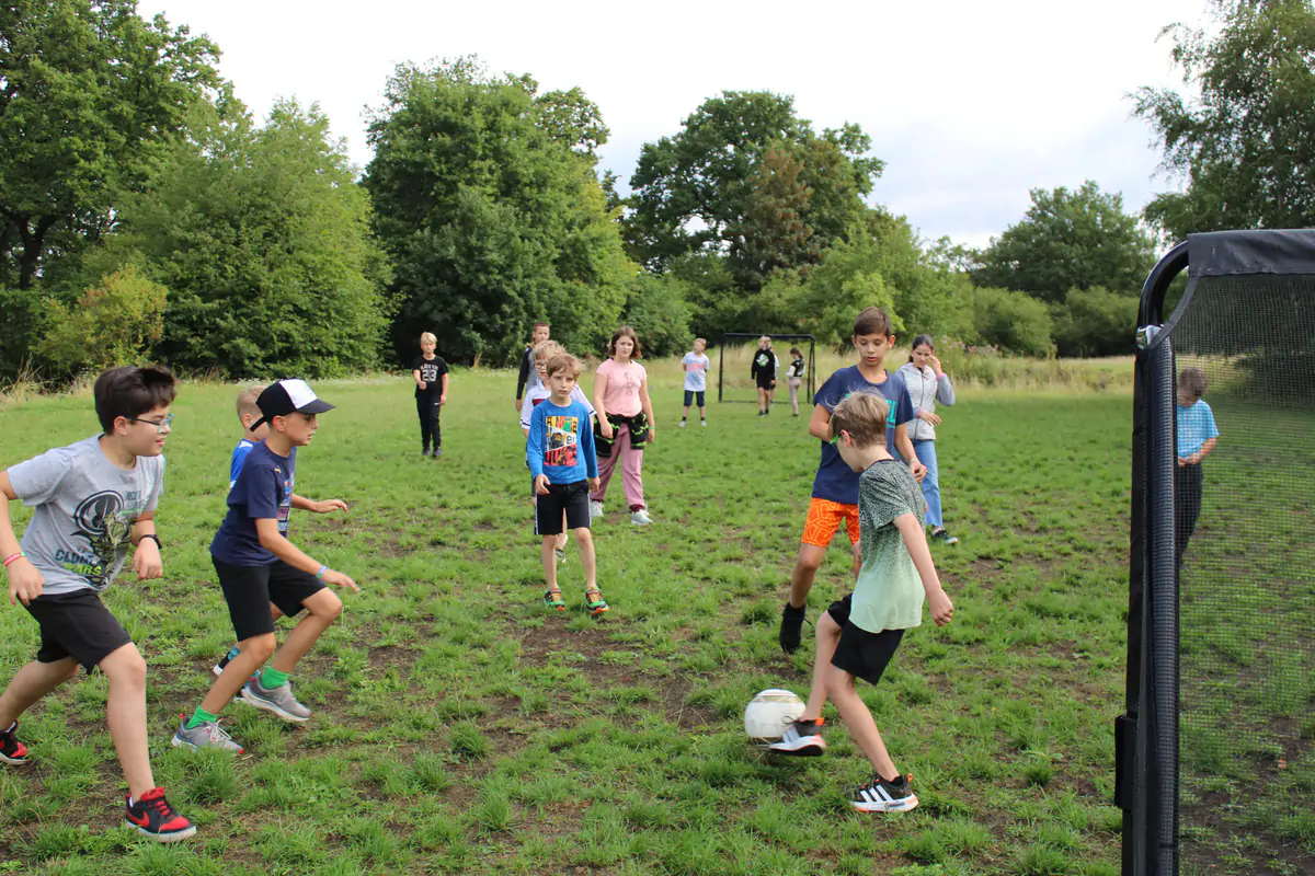 Children playing a ball game on the grass meadow in the grounds of the Beginner Weeks camp in Vallendar