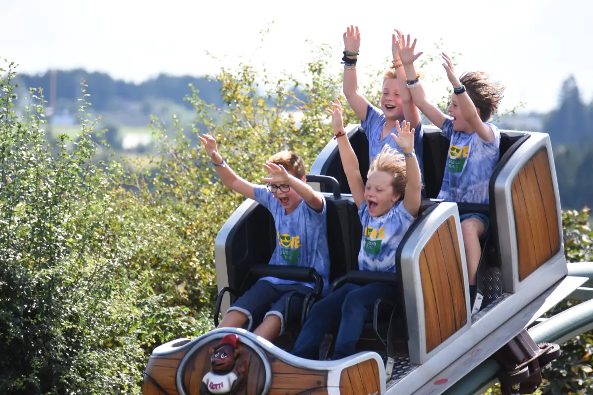 Children with their arms in the air riding the roller coaster on the day trip to the wildlife and adventure park