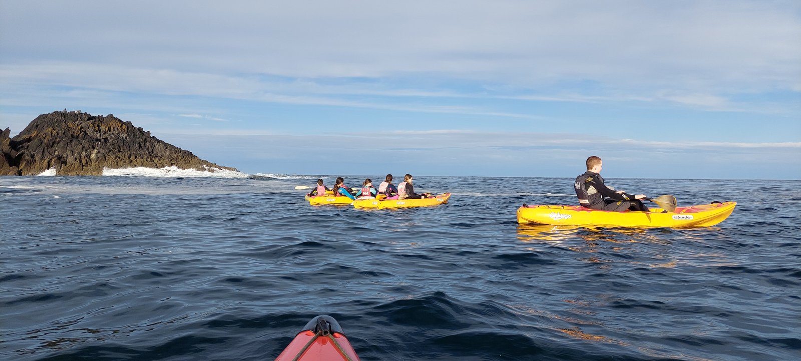 Kayakers paddling along the cliffs off Cape Clear Island