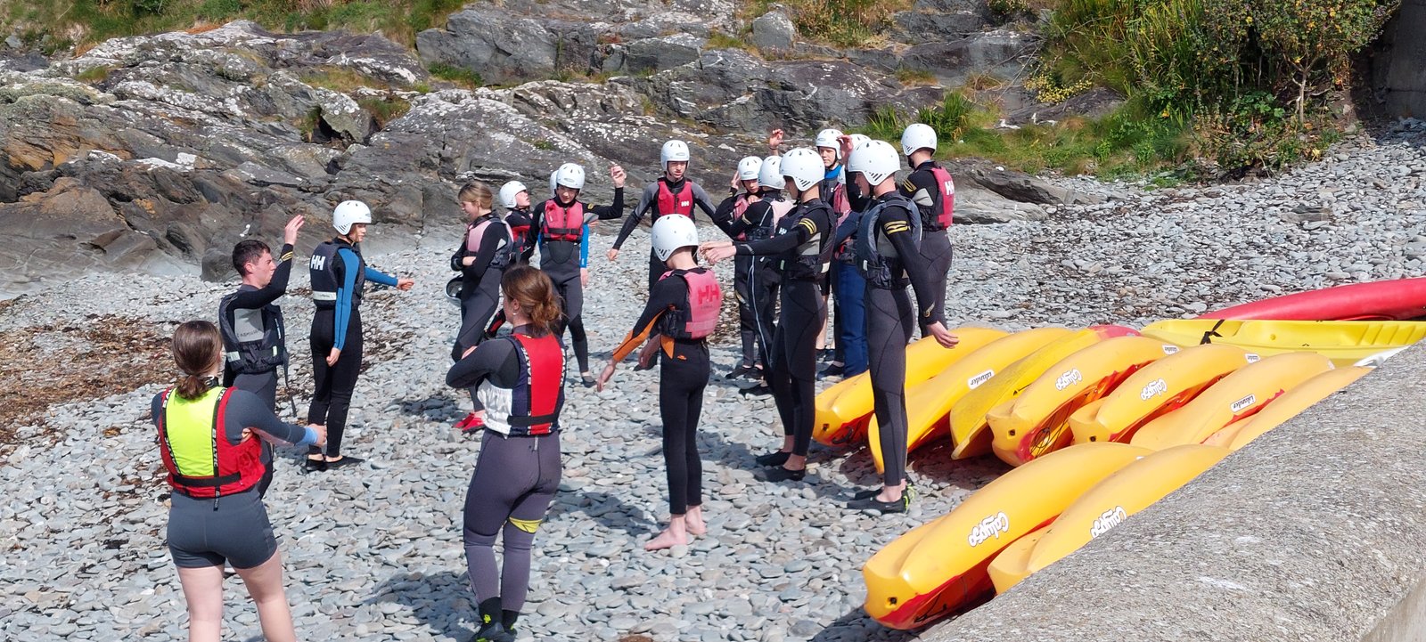 Participants in wetsuits and helmets beside the kayaks on the shore of Cape Clear Island