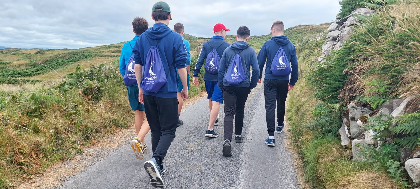 A group walking along an island road with day packs