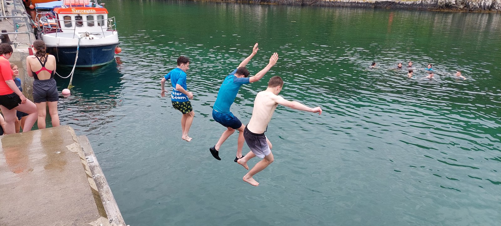 Participants jumping from the pier into the harbour