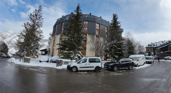 Exterior of the accommodation building at the foot of the slopes with snow on the ground and cars parked outside