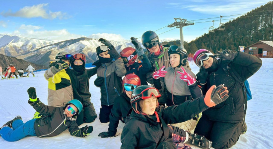 The group in ski gear posing together at the foot of the piste beside the lift