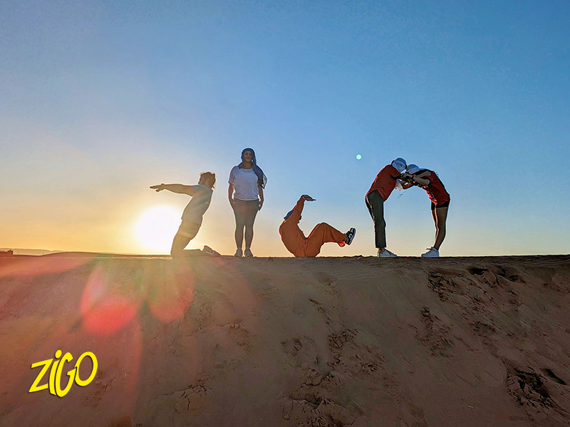 Three young participants in wetsuits standing behind surfboards on the Atlantic beach