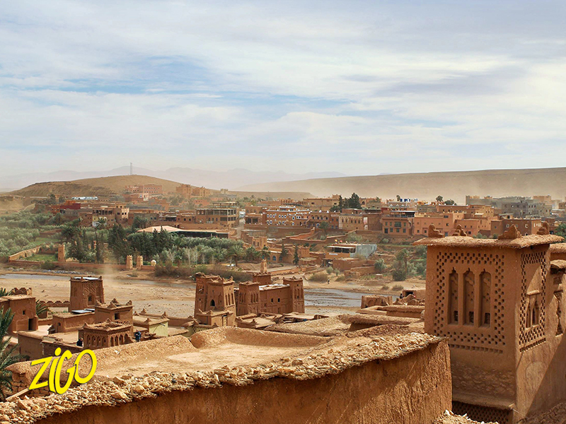 Participants wading the shallow river below the mud-brick kasbah of Ait Ben Haddou, Morocco