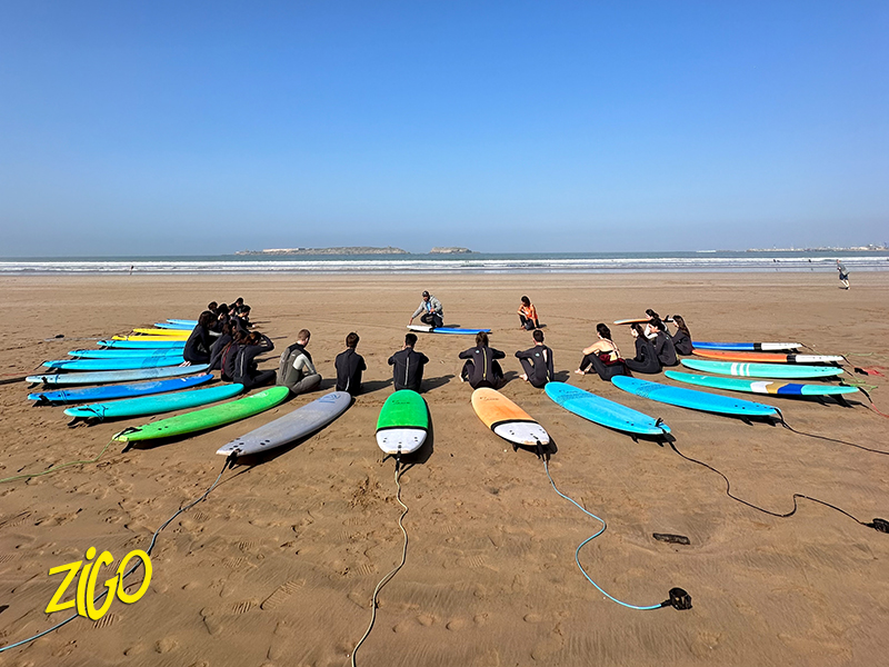 Surfboards laid out on the sand with a group entering the water during the introduction to surfing on the Atlantic coast