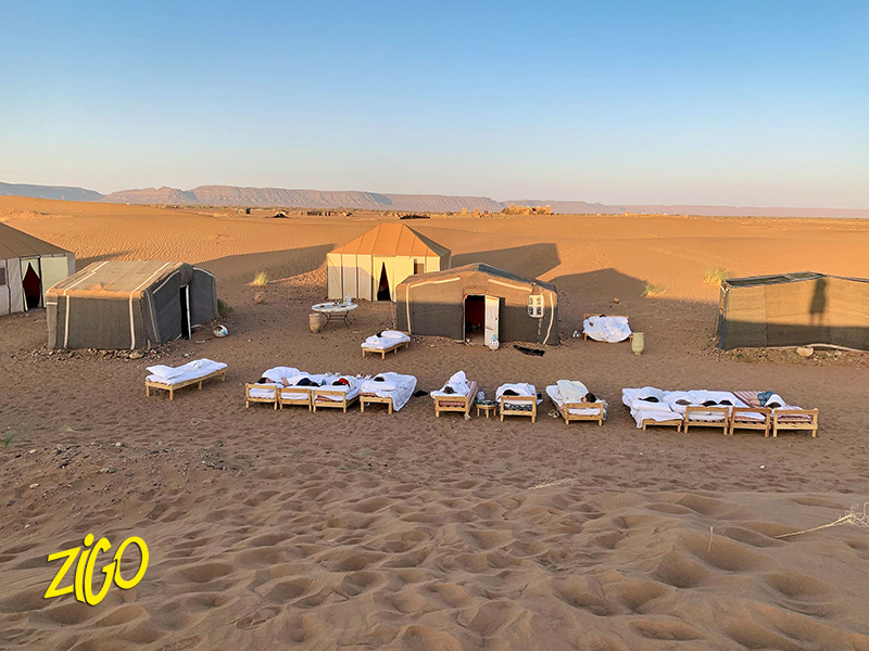 Berber tents and low beds set out on the sand at the desert camp used for the night under the stars