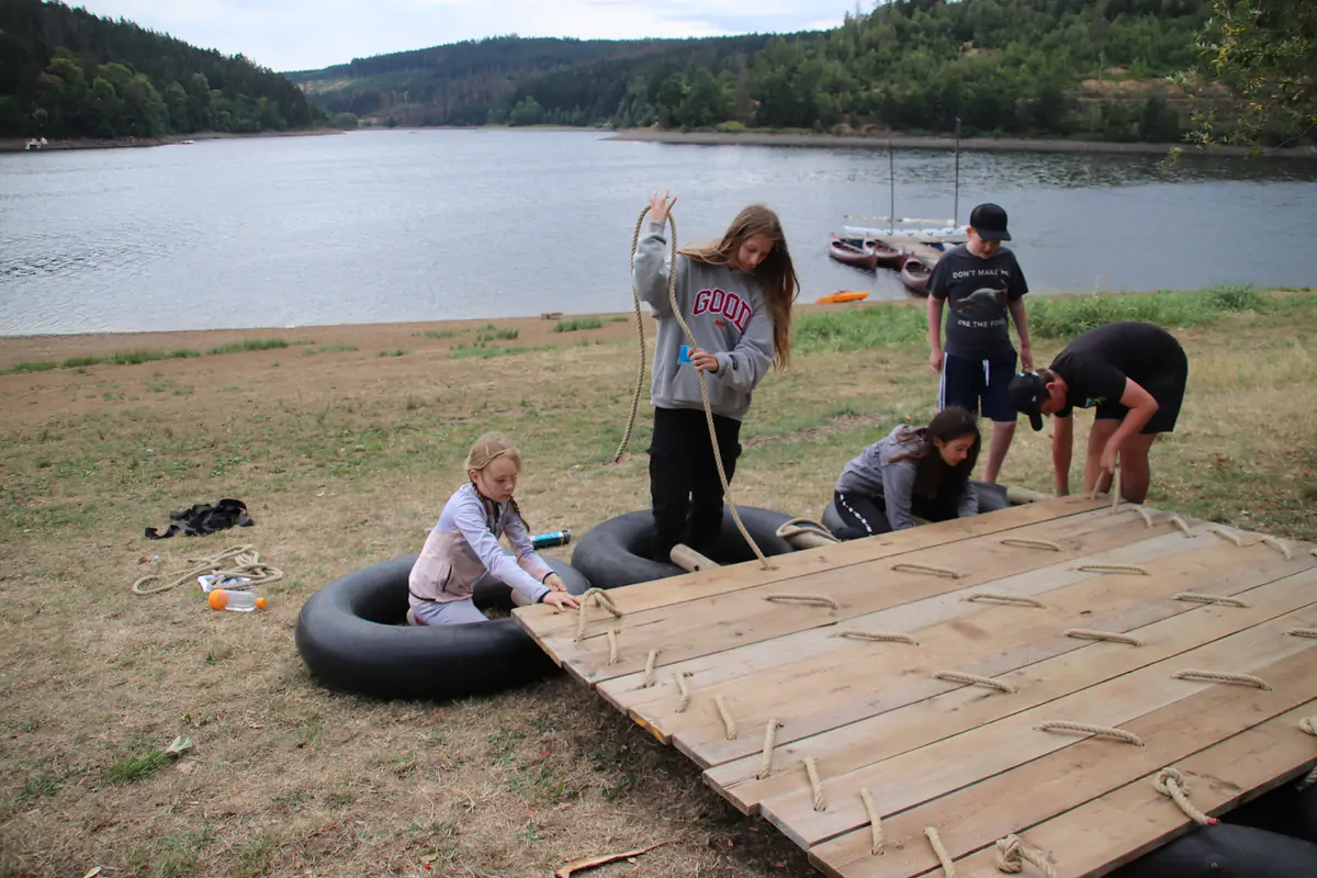 Children building a raft from tyres and boards on the shore of the reservoir
