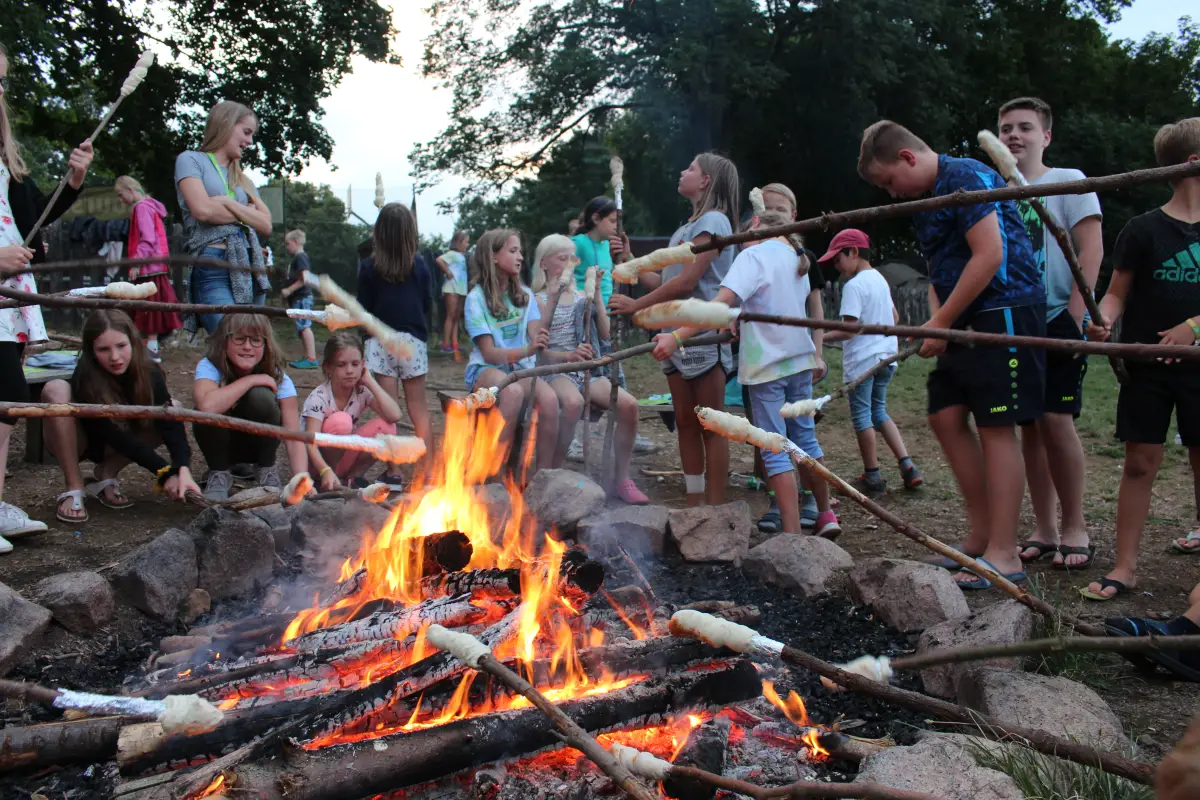 Children toasting stick bread over a campfire