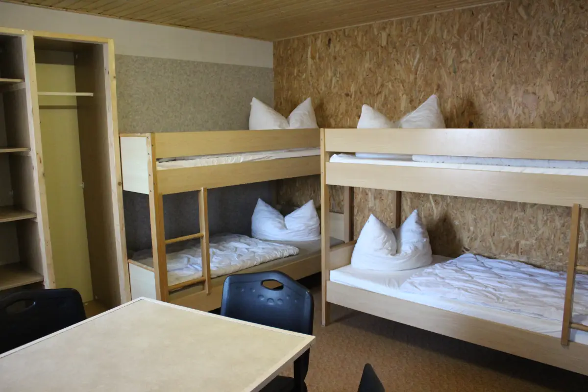 Room with two bunk beds and a small table