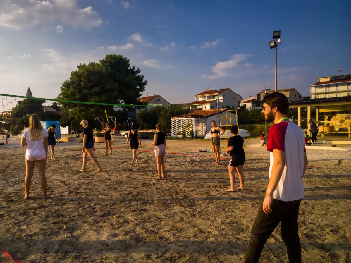Participants playing beach volleyball on the sand in the late afternoon