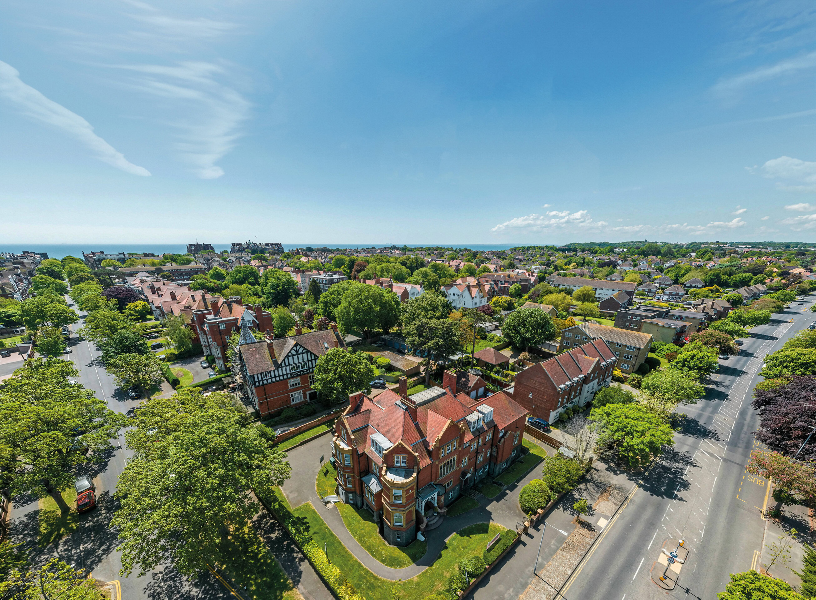 An aerial view of the Earlscliffe campus in Folkestone, its red-brick houses set among trees with the town and the sea beyond