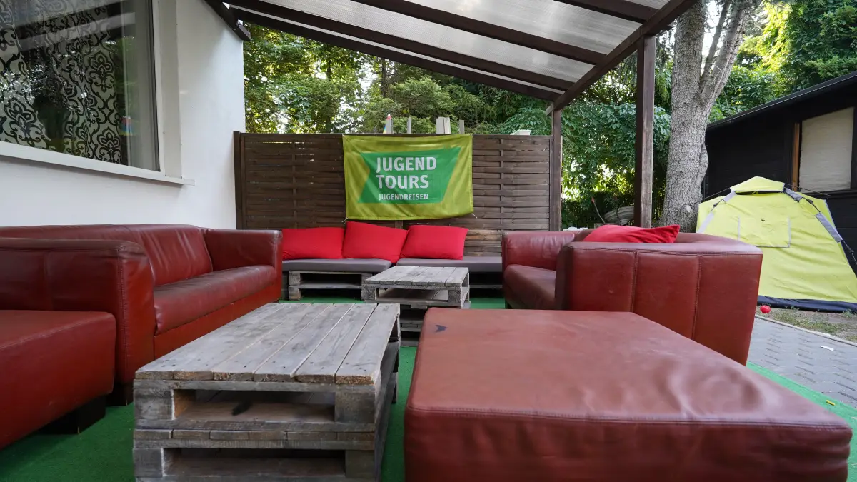 Covered outdoor lounge with red leather sofas and pallet tables at the Omega complex
