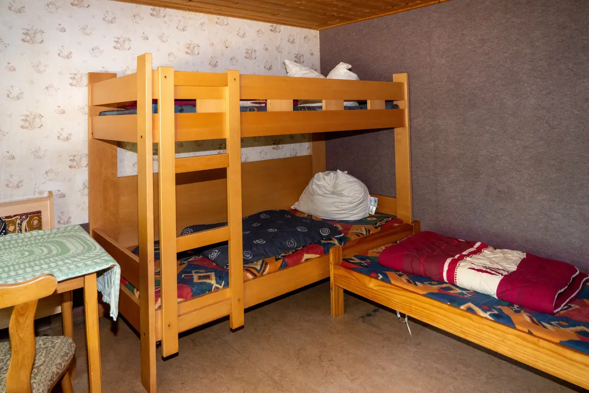 Bungalow room with a wooden bunk bed, a single bed and a small table