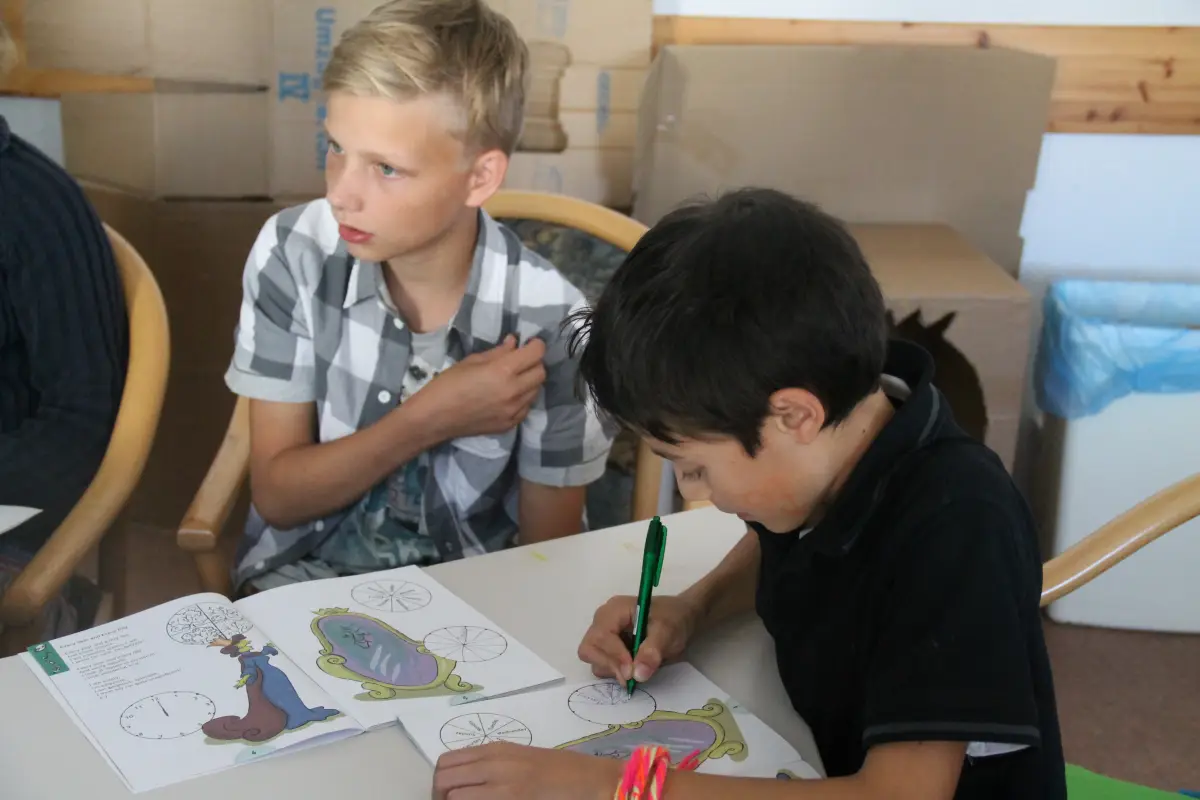 Two boys filling in an English worksheet at a table