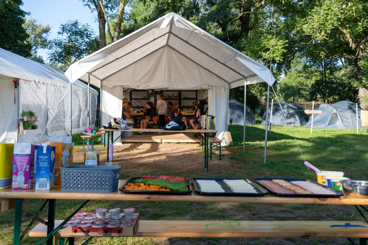 The open-fronted kitchen tent with crates of supplies and food laid out on trestle tables