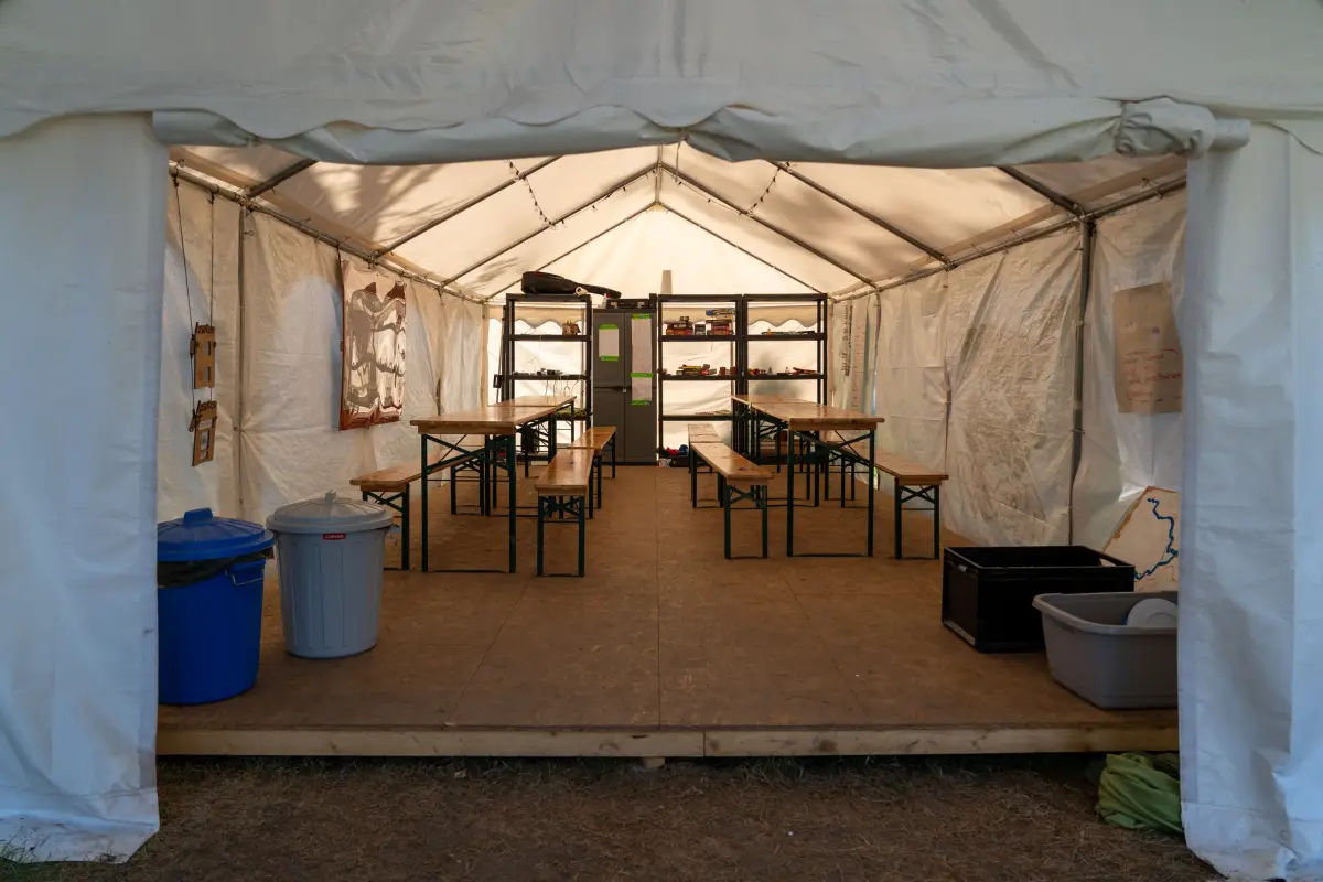 The inside of the large group tent set up with wooden tables and benches as the common room