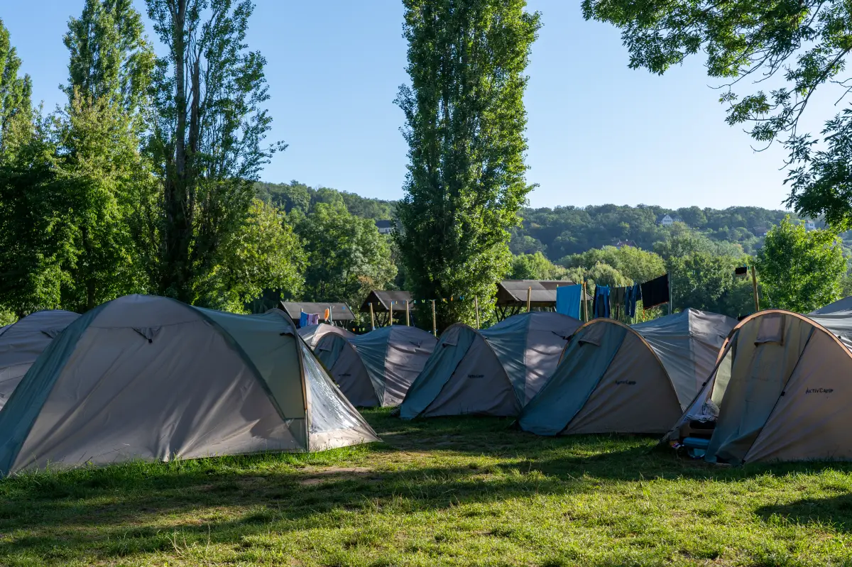 The field of igloo tents at the Aktivcamp with the wooded slopes of the river valley behind