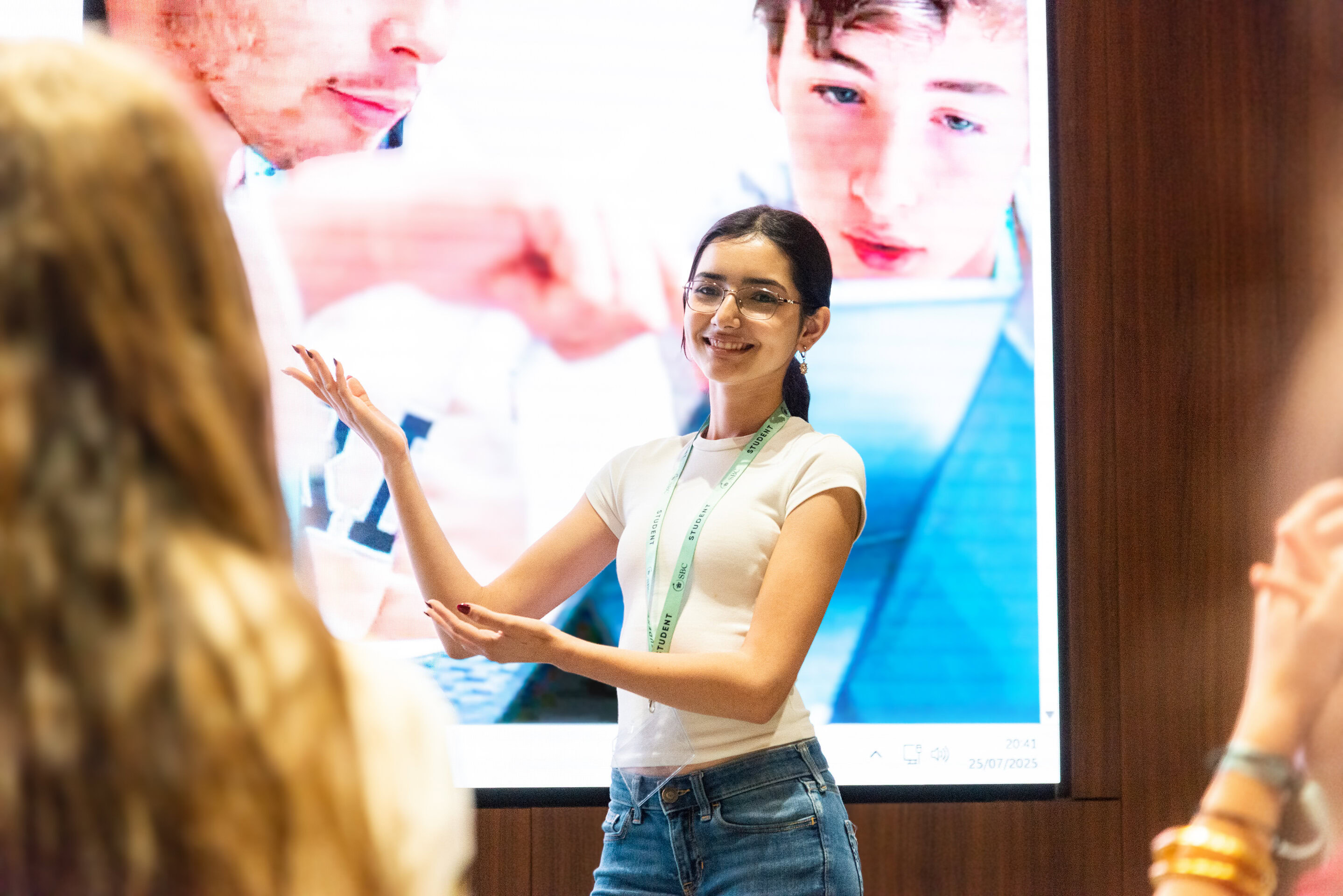 A student gives a presentation in front of a large screen showing medical images