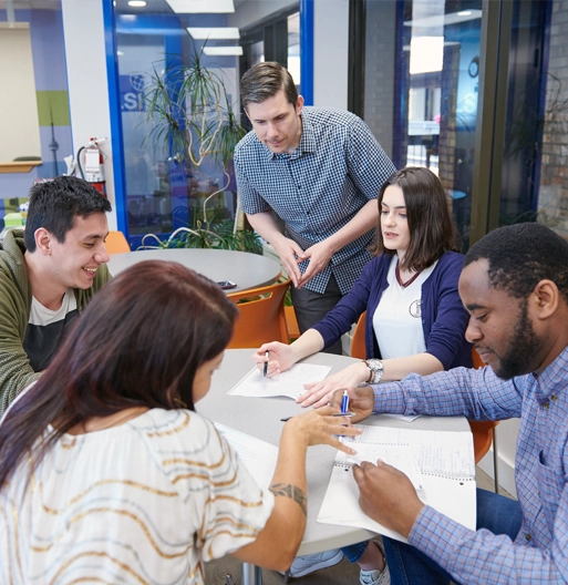 A small group working together around a table with a teacher helping them at LSI Toronto.