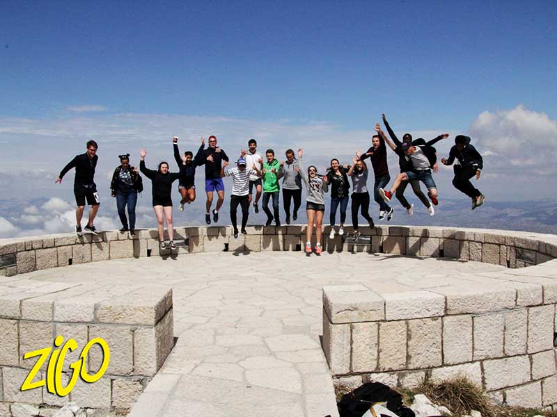 The group jumping together on a stone viewpoint terrace