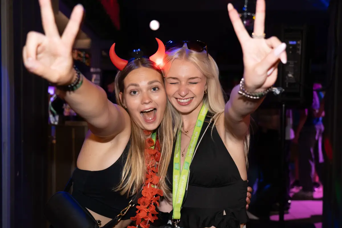 Two participants with raised hands at an evening party, wearing medals and costume horns
