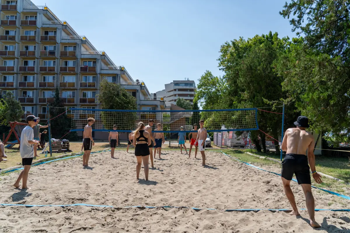 A beach volleyball game on the sand court in front of the hotel buildings