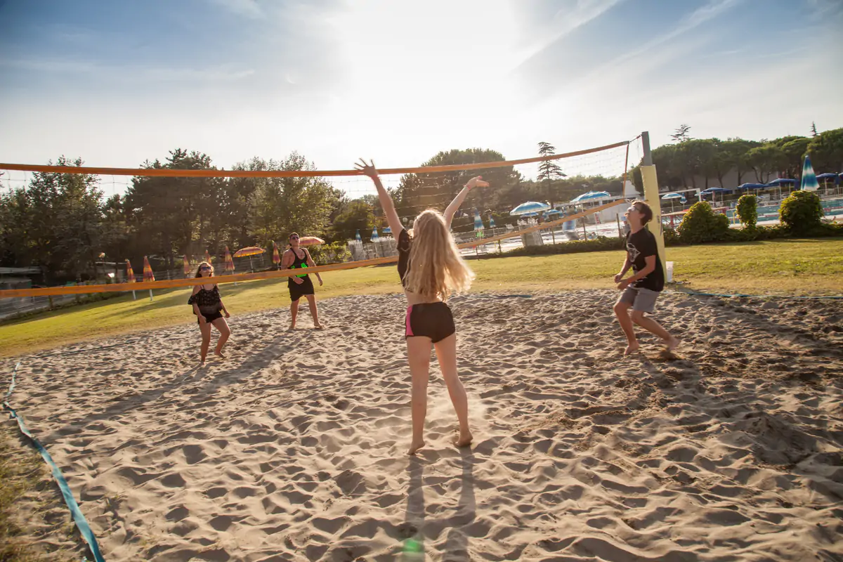 Teenagers playing beach volleyball on a sand court