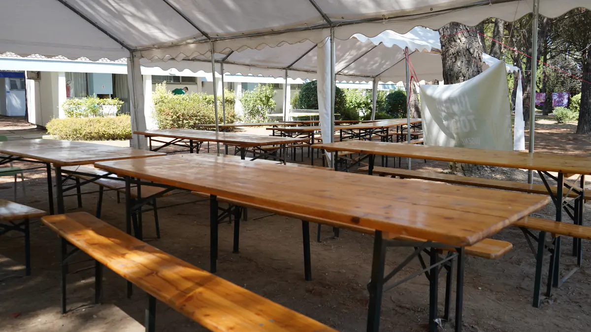 Long wooden tables and benches under a white marquee