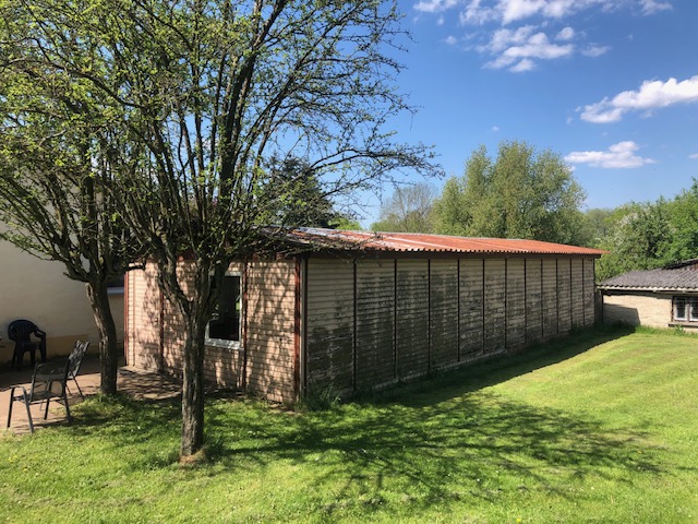 Lawn with trees and a long wooden outbuilding on the grounds of the Rüstzeitheim Schorfheide