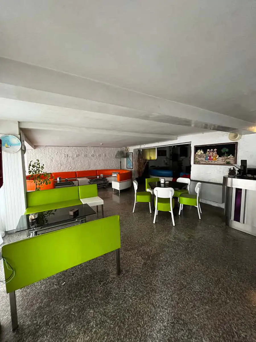 Hotel breakfast room with green serving counters and white chairs in the Jugendtours hotel in Rimini Miramare