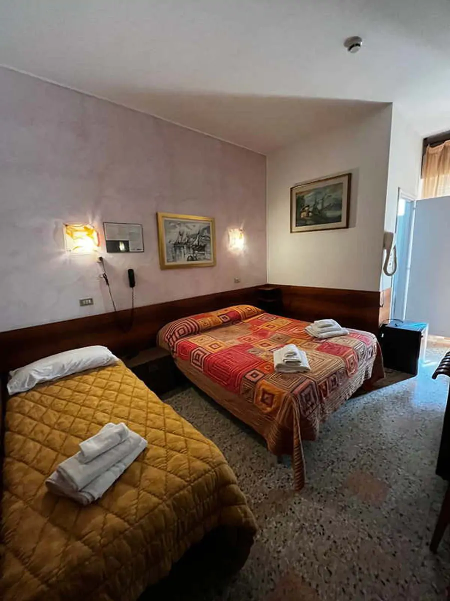 Twin room with two beds, folded towels and a framed picture in the Jugendtours hotel in Rimini Miramare