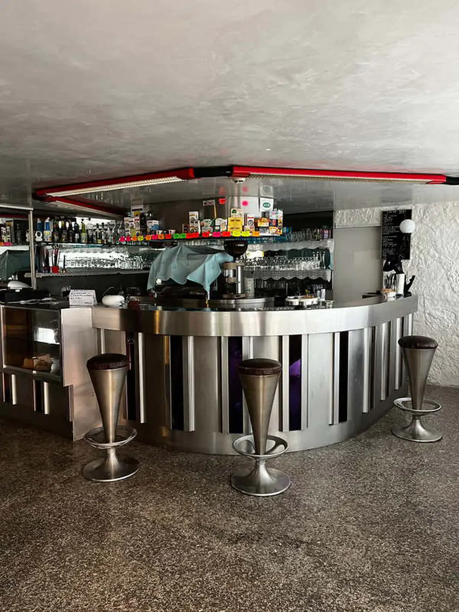 Curved hotel bar counter with stools and a stocked back bar in the Jugendtours hotel in Rimini Miramare