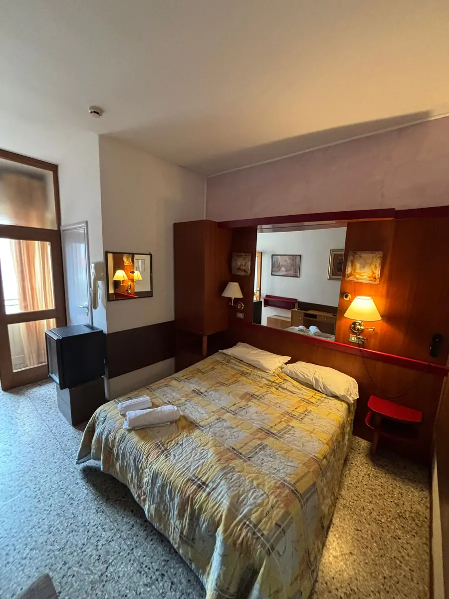 Hotel bedroom with a double bed, bedside lamps and a mirrored wardrobe in the Jugendtours hotel in Rimini Miramare