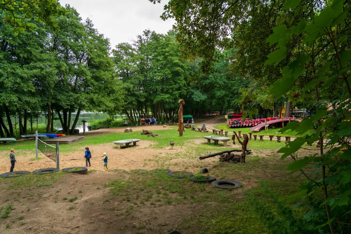 The sandy beach and open sports ground of the campsite, fringed by trees