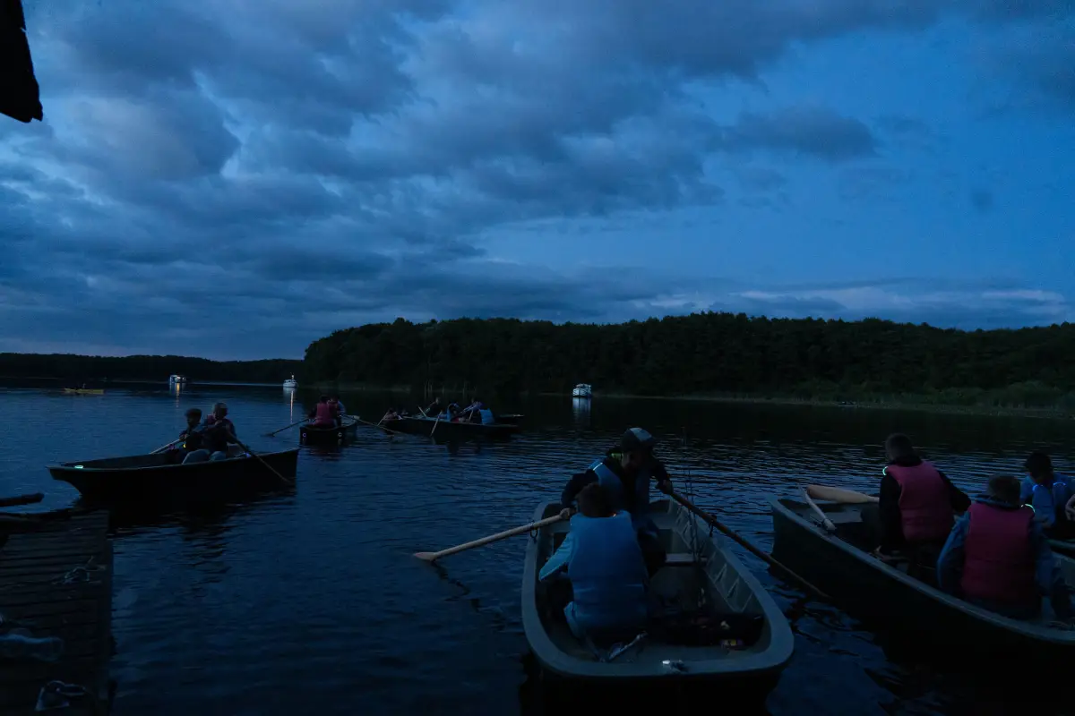 Campers out on the lake in a boat with their rods as the light fades