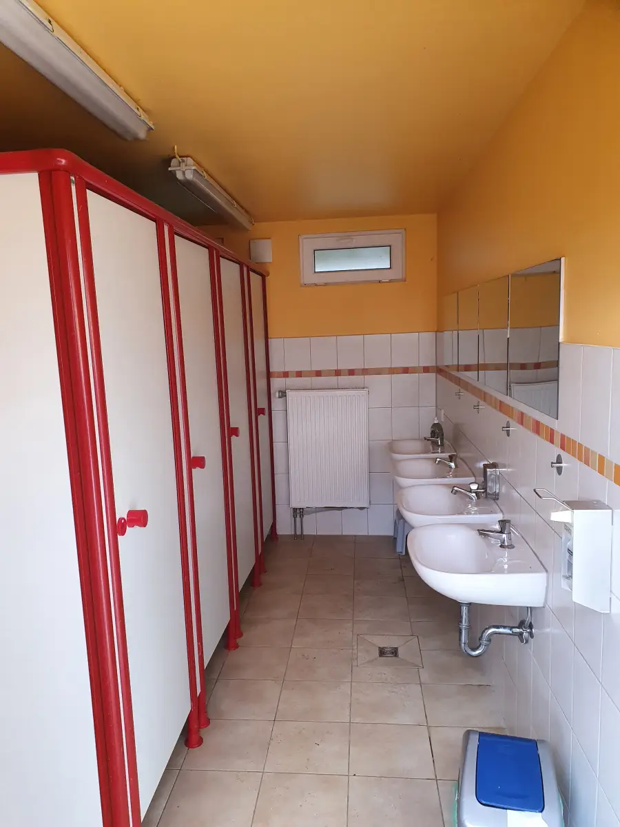 The sanitary block inside, with a row of washbasins and red-doored shower cubicles