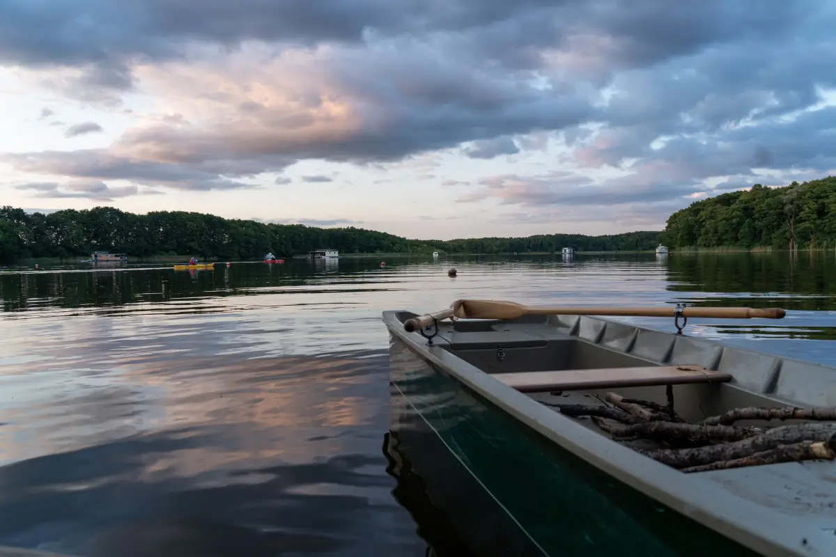 A rowing boat moored at the shore with the lake and a bank of cloud beyond at dusk