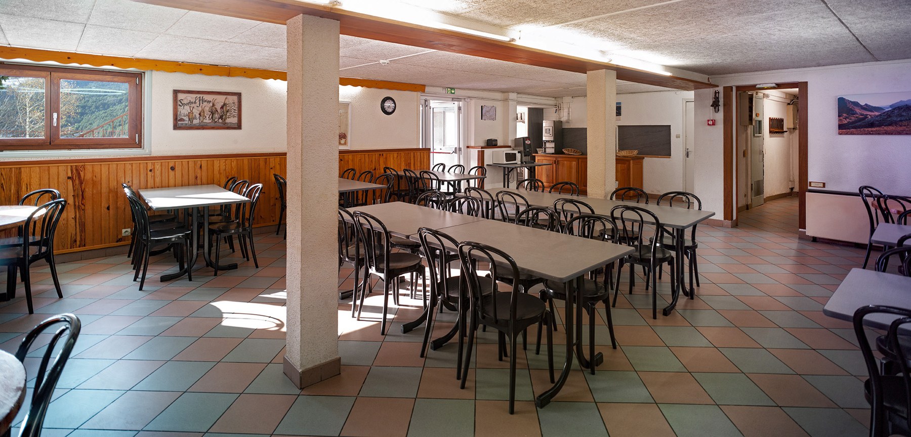 Dining room at the Anjou Vanoise centre with tables and chairs, tiled floor and wood-panelled walls