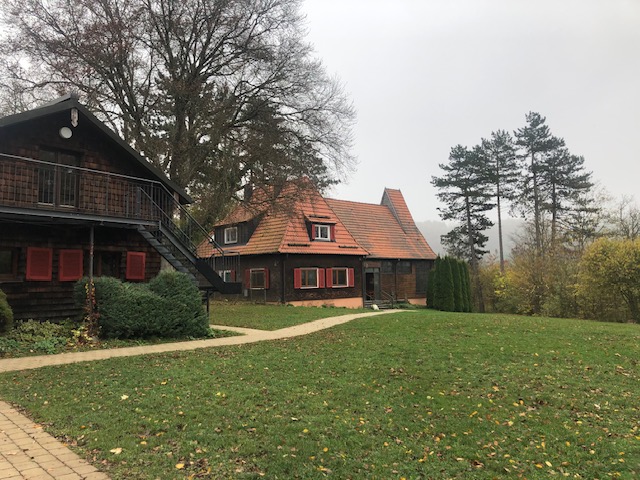 Lawn and footpath between the log house and a red-roofed building at the Schwarzhornhaus site