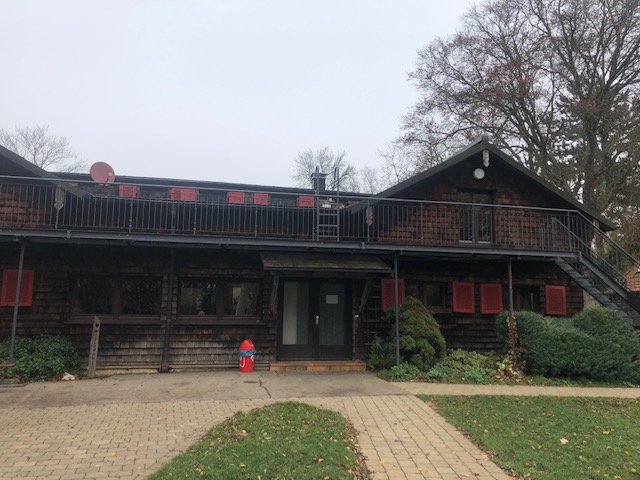 Front of the log-built Schwarzhornhaus with red shutters and a paved path to the entrance