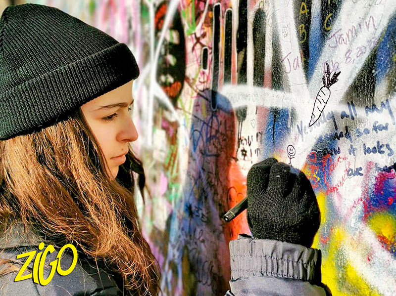 Writing a message on the John Lennon wall