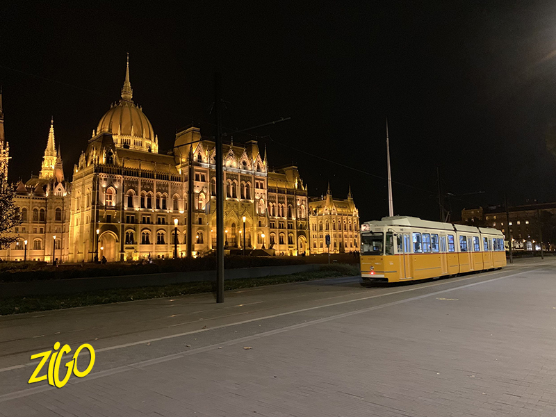 The Hungarian Parliament lit up at night with a passing tram