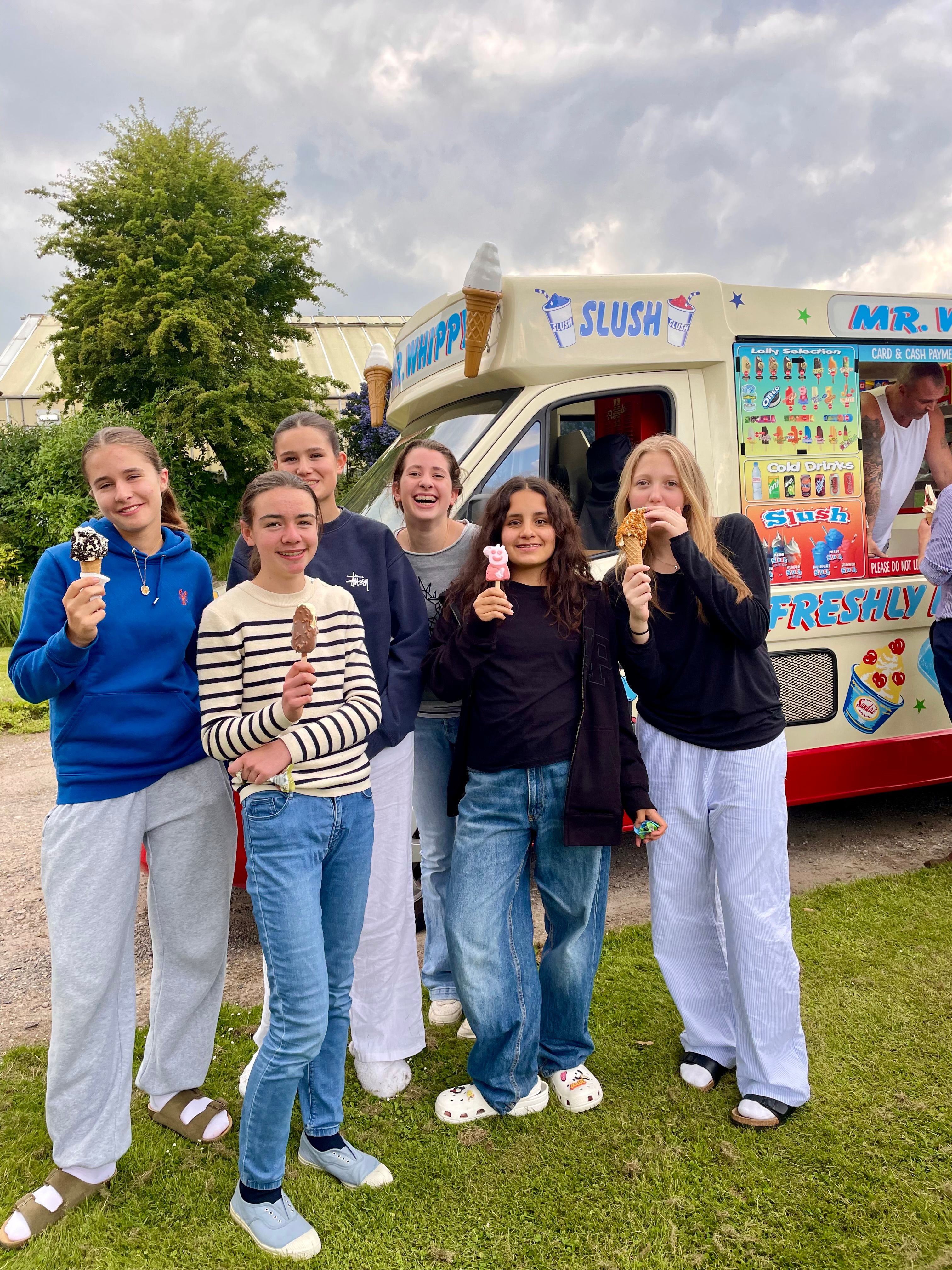 A group of Cobham Hall students with ice creams beside an ice cream van on the school grounds