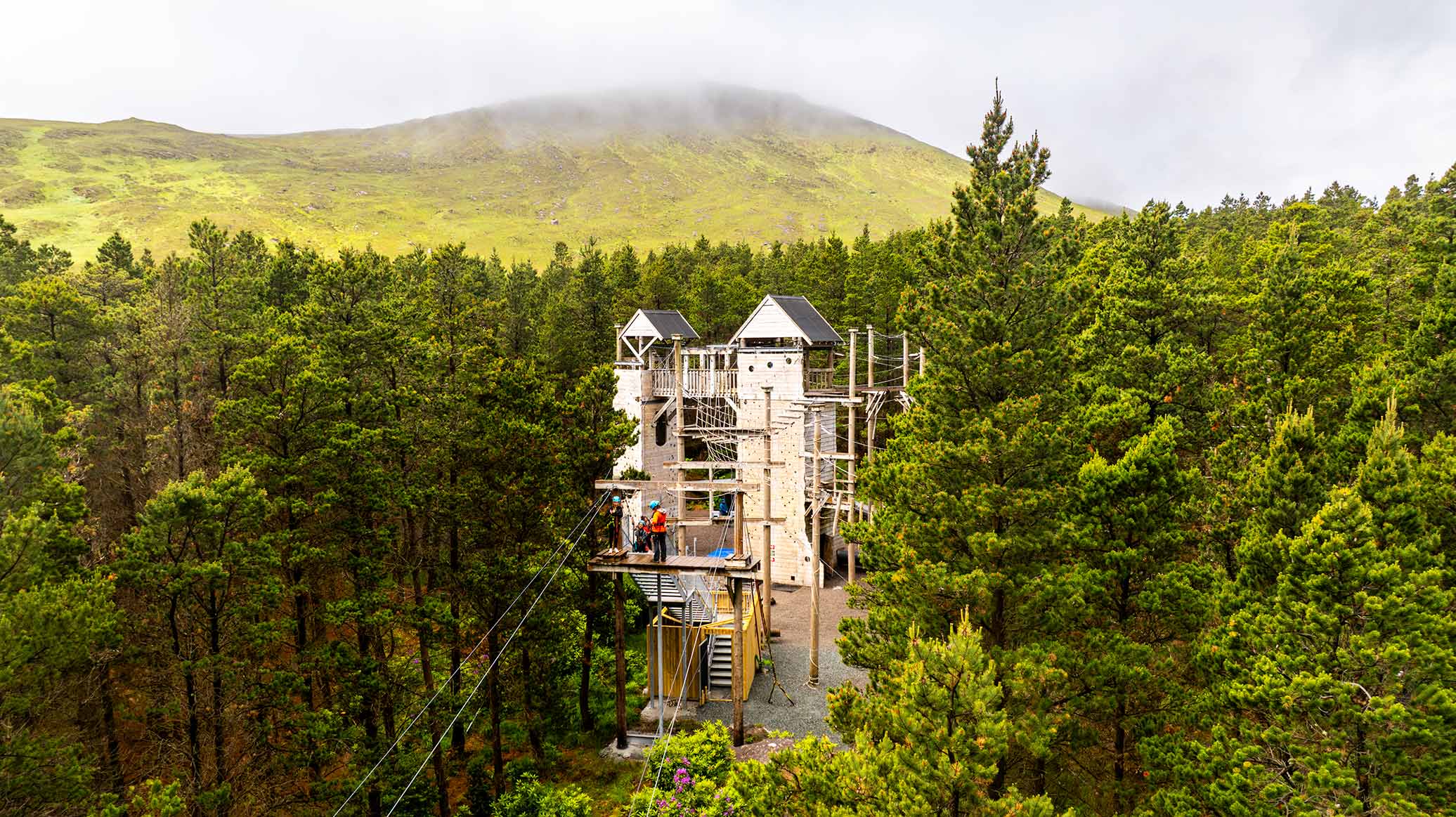 Wooden high ropes tower rising above conifer forest at Delphi Resort, Connemara