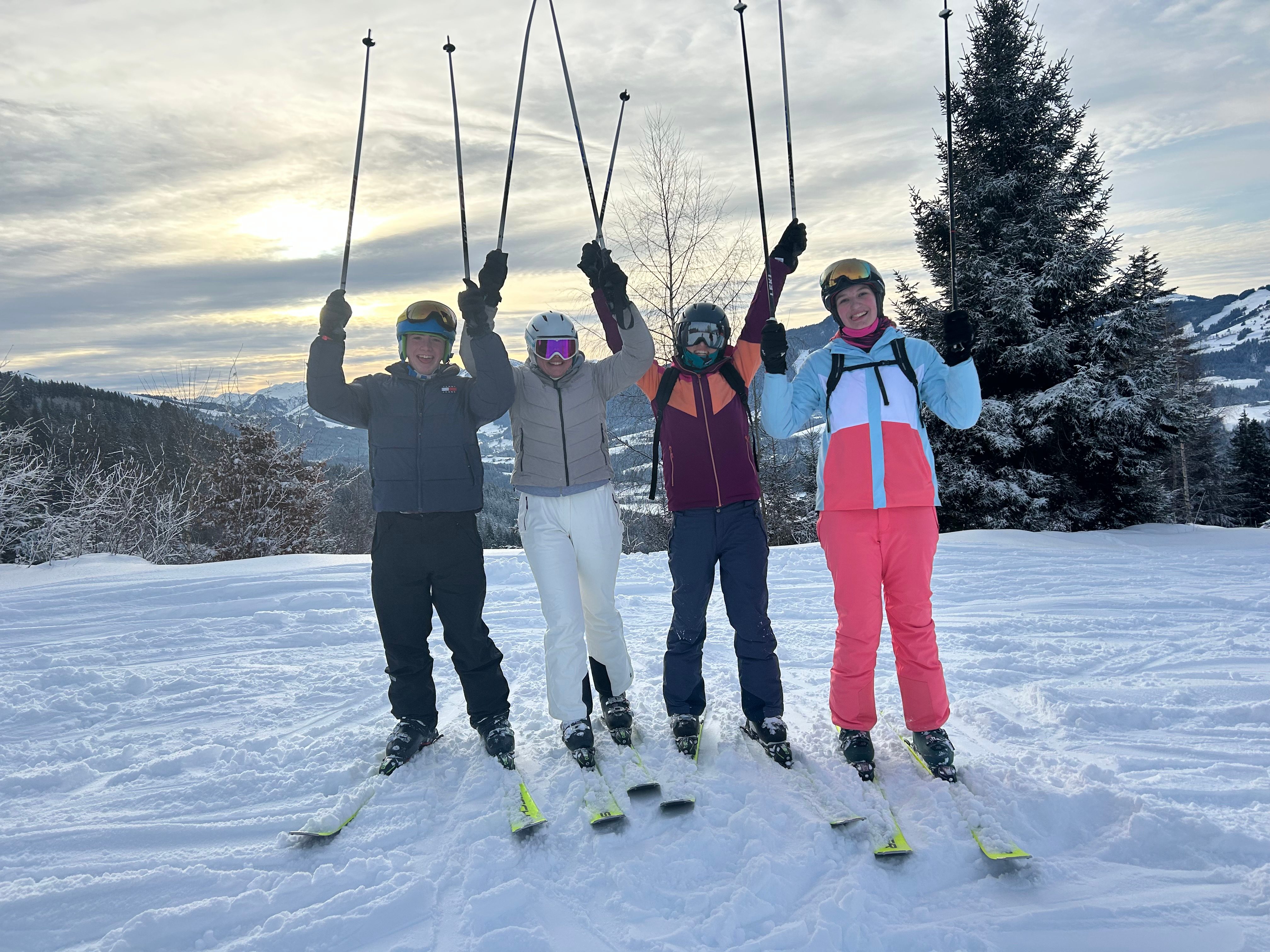 Group posing for a photo in the snow holding ski poles