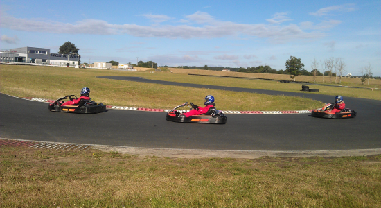 Two go-karts running side by side on the outdoor circuit used by the camp