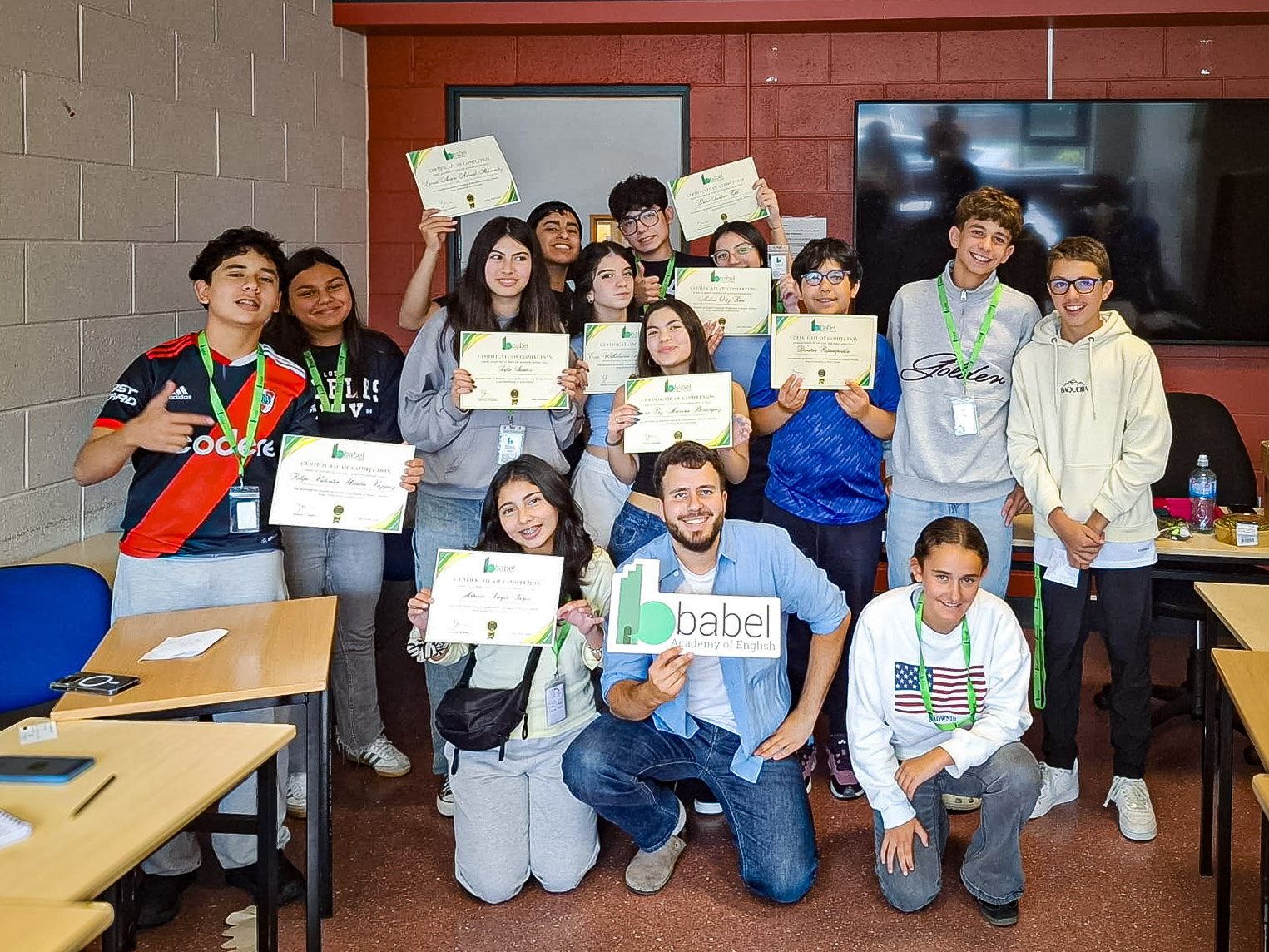 A class of teenage students with their teacher holding course certificates in a classroom on the last day at DCU