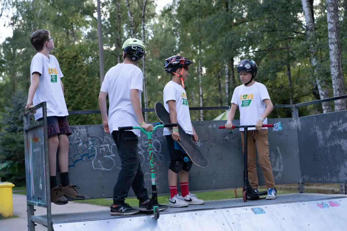 Children with scooters and helmets at the skate ramp